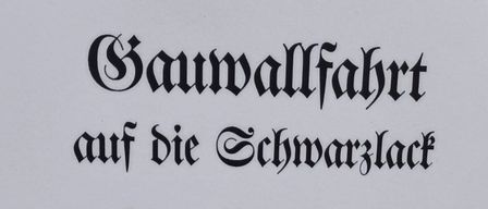 Ein schwarz-weißes Plakat mit einer gotischen Schrift kündigt eine Baumpflanzaktion am 23. August 2026 um 9:00 Uhr in Brannenburg an.