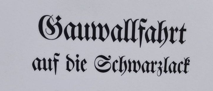 Ein schwarz-weißes Plakat mit einer gotischen Schrift kündigt eine Baumpflanzaktion am 23. August 2026 um 9:00 Uhr in Brannenburg an.