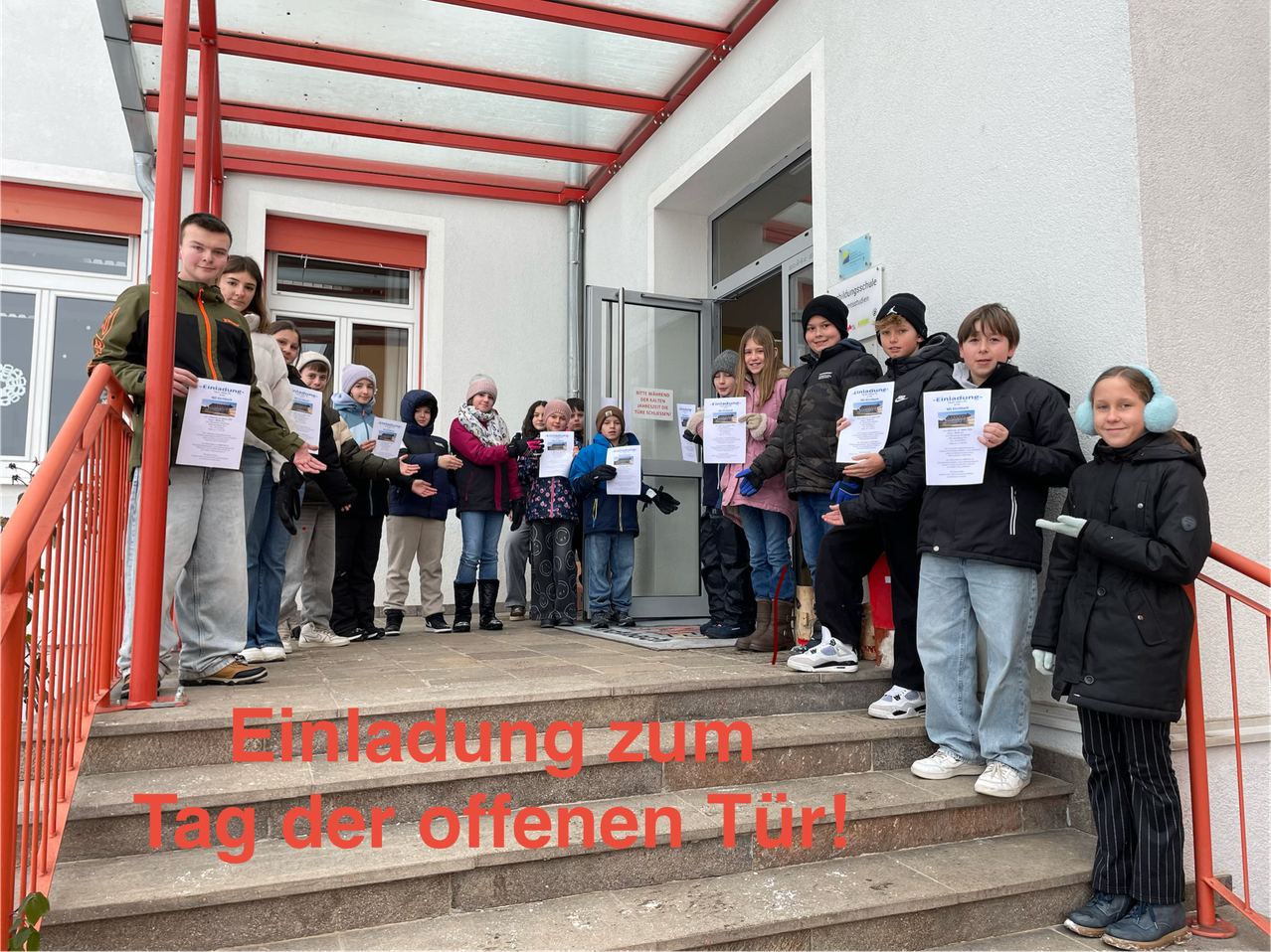 Eine Gruppe von Kindern und Erwachsenen posiert auf den Stufen eines Gebäudes und hält Schilder, auf denen 'Einladung zum Tag der offenen Tür!' steht. Das Bild hat eine festliche Atmosphäre, und sie scheinen auf eine Veranstaltung zu warten.