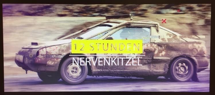 Ein Poster eines schmutzigen Autos mit einem gelben Banner, das '12 STUNDEN NERVENKITTEL' besagt. Das Auto scheint auf einer schlammigen Straße zu fahren.