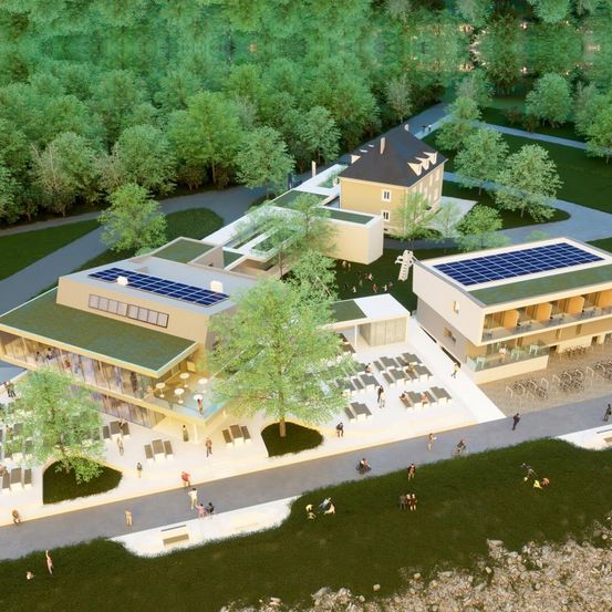 Eine Luftaufnahme eines modernen architektonischen Entwurfs mit zwei Gebäuden mit Solarmodulen auf ihren Dächern. Das Gebiet ist von üppiger Vegetation umgeben und Menschen gehen herum.