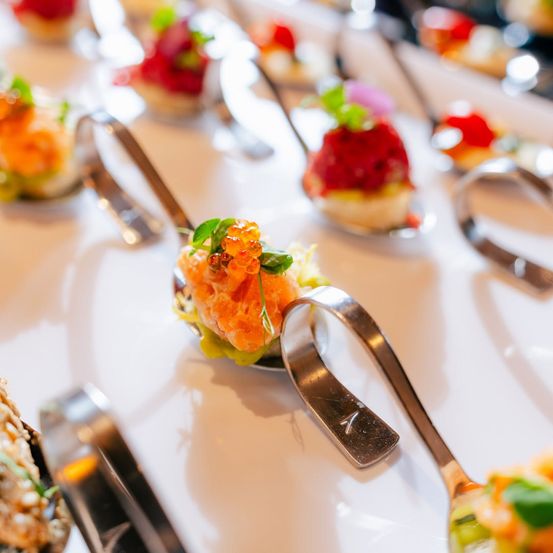 Eine Nahaufnahme einer Auswahl an Gourmet-Gerichten auf Löffeln, garniert mit bunten Zutaten und Kaviar.