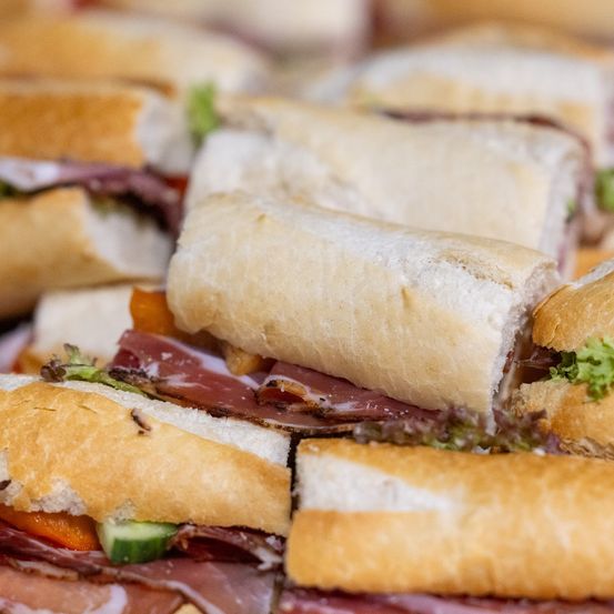 Eine Nahaufnahme verschiedener Sandwiches mit verschiedenen Füllungen, einschließlich Fleisch, Salat und Gurke. Die Sandwiches sind auf einem Teller platziert.