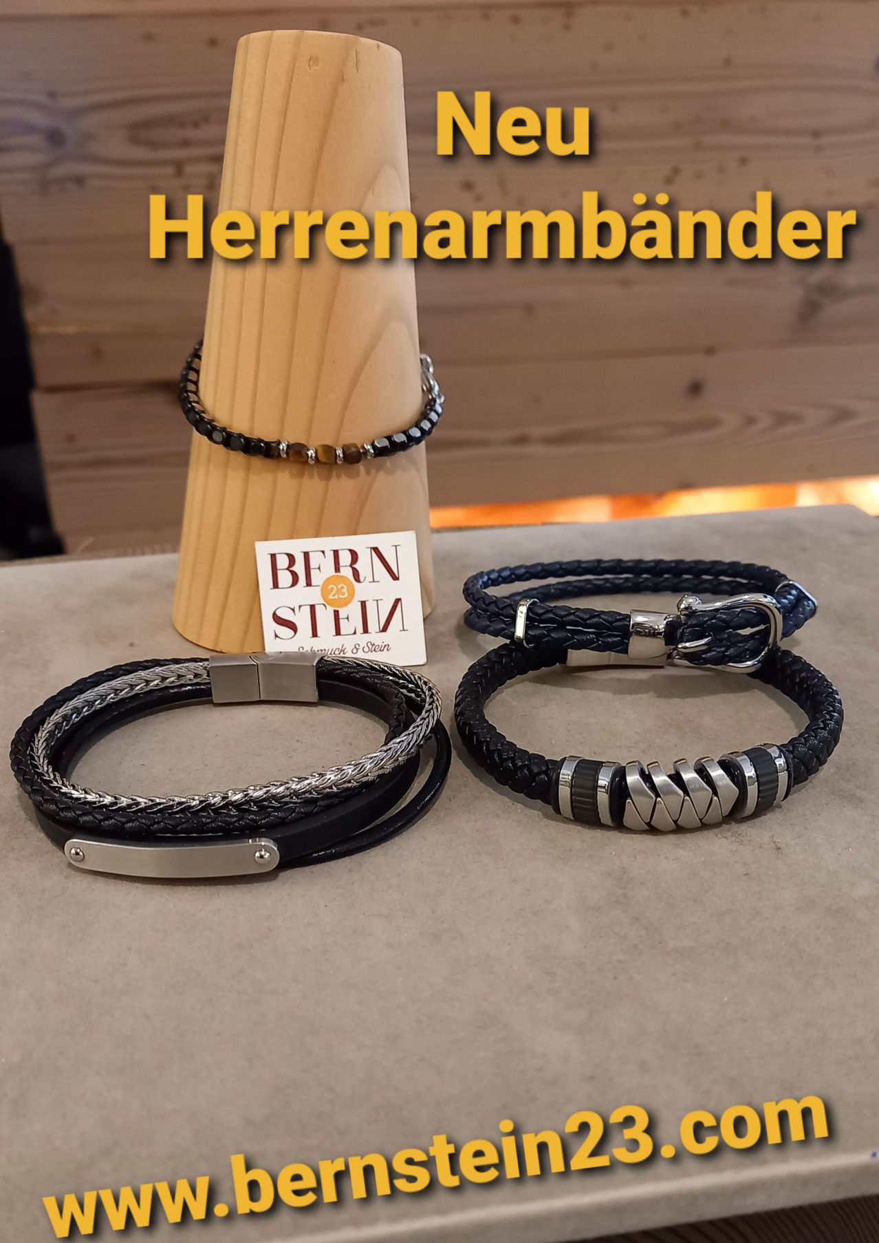 Drei Lederarmbänder auf einer Holzausstellung. Ein schwarzes und silbernes, ein schwarzes mit silbernem Verschluss und ein schwarzes und silbernes mit einem Zickzack-Muster.
