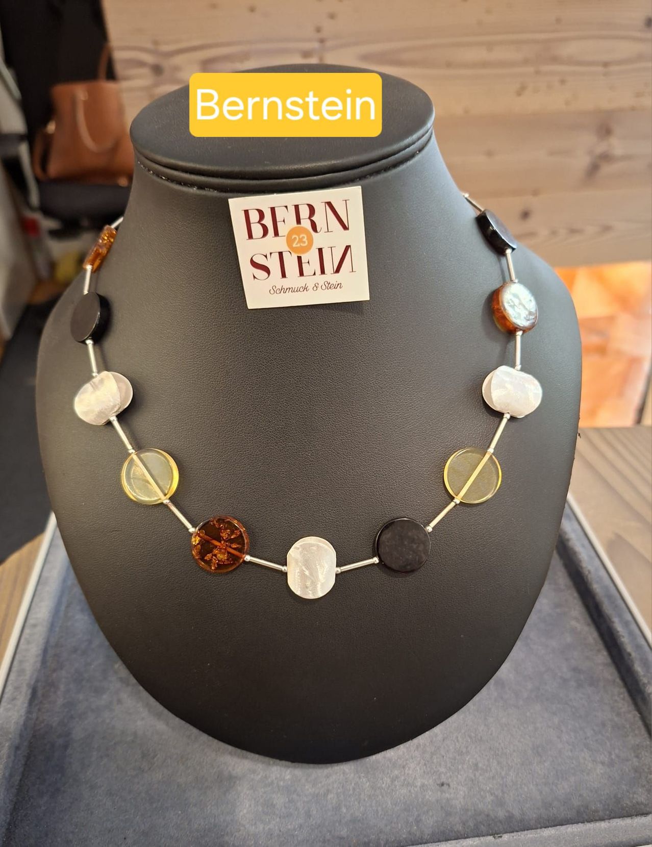 A necklace with various colored beads displayed on a mannequin with a tag reading 'Bernstein'.