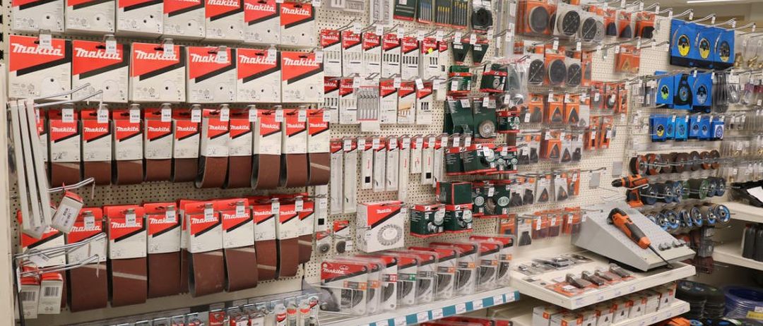 Ein Geschäft mit verschiedenen Makita-Produkten zur Ausstellung, einschließlich Werkzeuge und Zubehör, ordentlich auf Regalen und Tafeln organisiert.