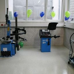 Ein Raum mit zwei blauen Maschinen, eine mit einem grünen und die andere mit einem blauen Ballon, und einem Trolley mit einem grünen und blauen Zylinder.