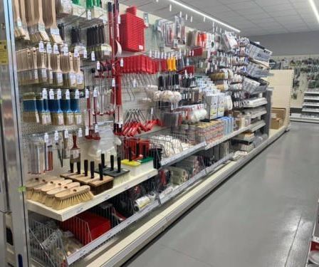 Ein Ladengang gefüllt mit verschiedenen Mal- und Reinigungswerkzeugen, einschließlich Pinsel, Walzen und Dosen, die ordentlich auf Regalen und Metallhakentafeln angeordnet sind.