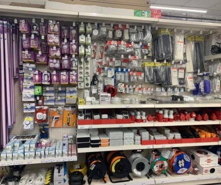 Ein Geschäft mit vielen Regalen, die mit verschiedenen Produkten wie Beleuchtung, Verkabelung und elektrischem Zubehör gefüllt sind. Jedes Regal hat ordentlich angeordnete Artikel, einige in bunten Verpackungen.
