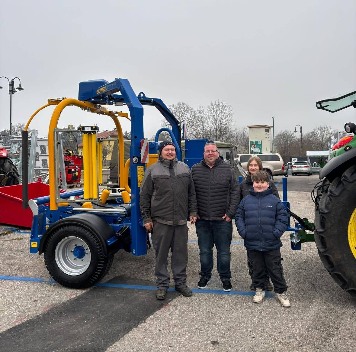 Eine vierköpfige Familie steht vor einem blau-gelben Fahrzeug, mit einem lächelnden Jungen.