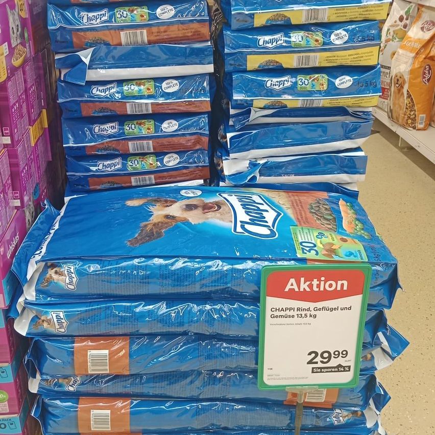 Stapel von blauen Tüten mit Chappi Hundefutter in einem Geschäft mit einem Verkaufsschild, das einen Preisnachlass anzeigt.