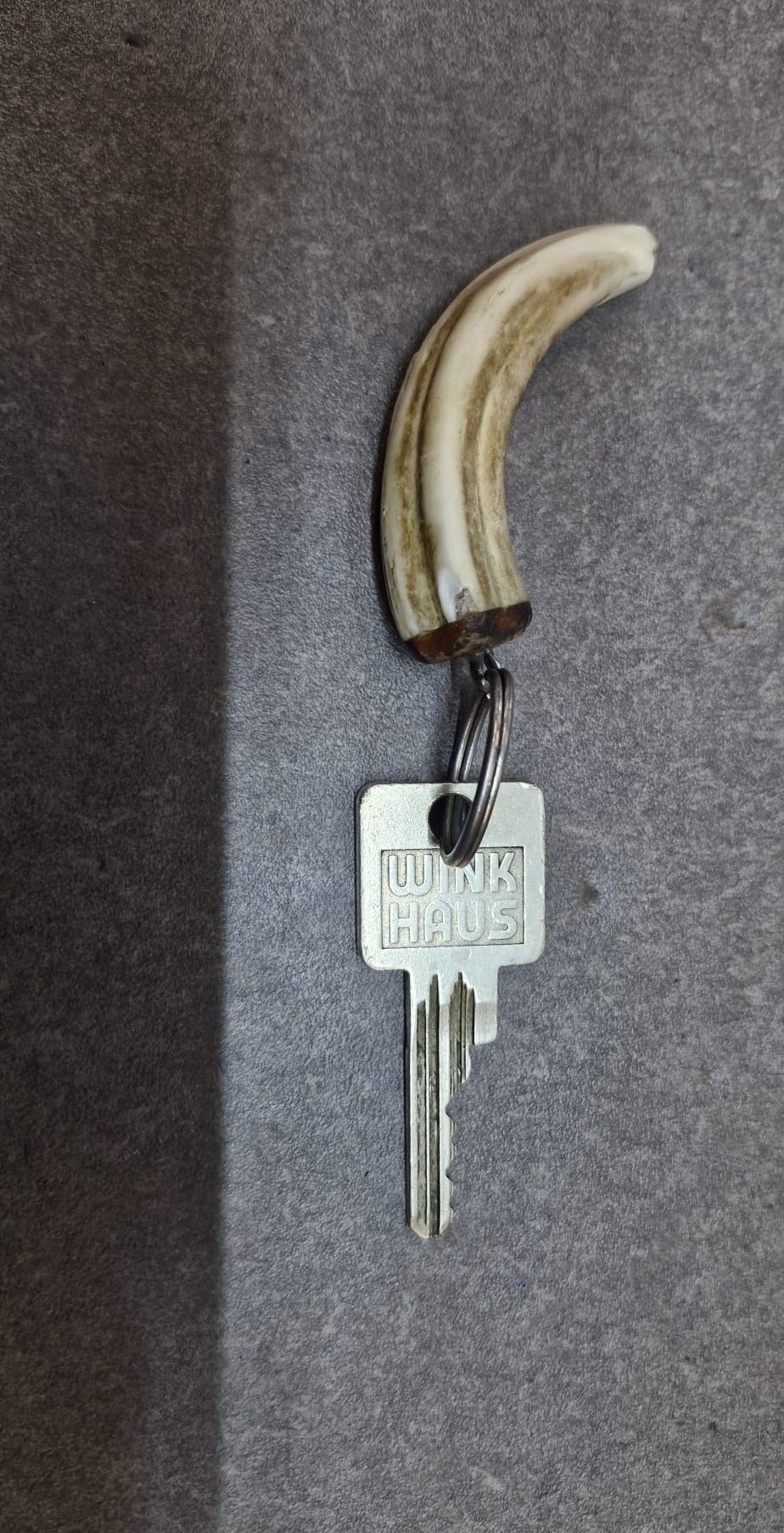 Ein silberner Schlüssel mit den Worten Wink Haus auf einem grauen Hintergrund. Der Schlüssel hat einen Horngriff.