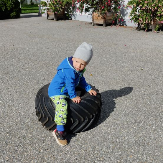 Bild enthält, Tire, Boy, Child, Male, Person, Alloy Wheel, Soil, Pants, Hat, Cap