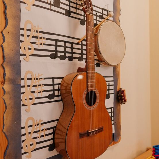 Eine Gitarre ist an einer Wand mit Musiknoten und einem Schlagzeug montiert und schafft ein lebhaftes Musikthema.