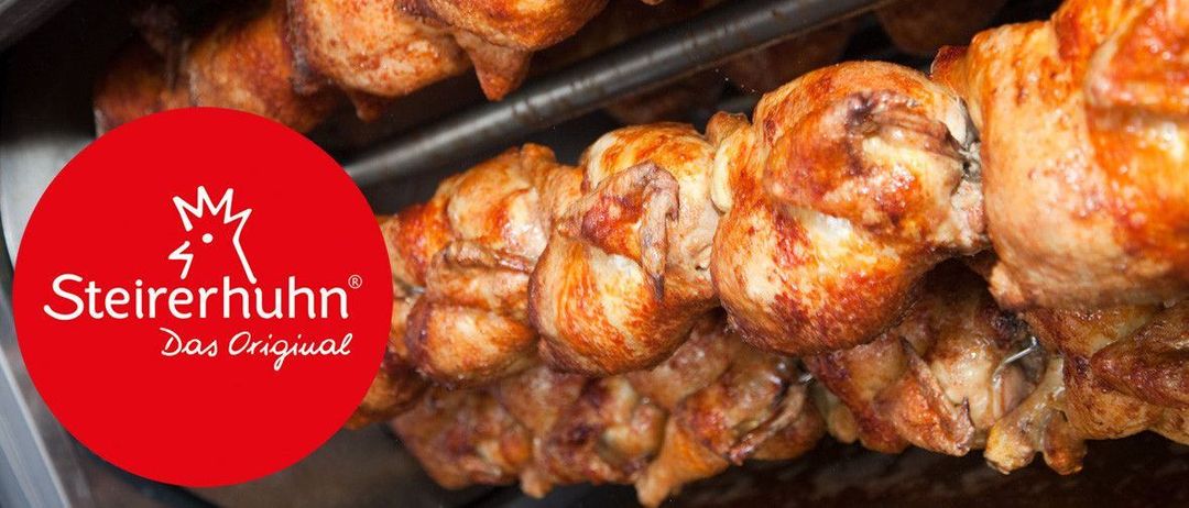 Nahaufnahme von mehreren gebratenen Hähnchenschenkeln in einem Metallrost, einige mit goldbrauner Haut, möglicherweise Teil einer kommerziellen Werbung.