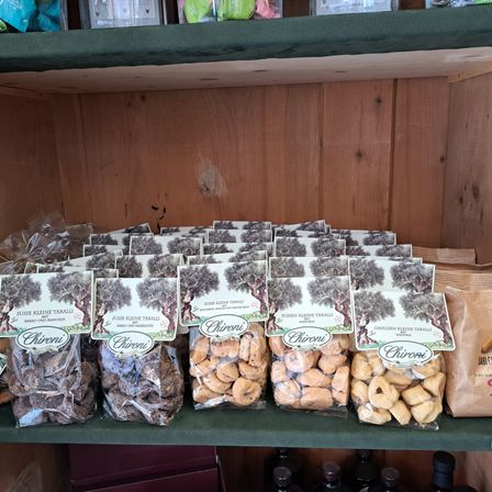 Ein Holzregal zeigt verschiedene Chioni-Snackpackungen in Klarsichtfolie, einschließlich Schokolade und Keksvarianten.