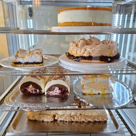 Eine Vitrine mit verschiedenen Desserts, darunter ein Käsekuchen, eine Meringue-Tarte, ein Schokoladenkuchen-Roll und ein Gebäck mit gelber Glasur.