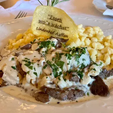 Ein Teller mit Beef Stroganoff, Kartoffelpüree und einem Brotchip mit der Aufschrift 'Essen wo's wächst'.
