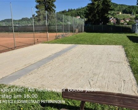 Ein leerer Tennisplatz, umgeben von einem Zaun. Ein sandiger Bereich mit einer Bank. Der Platz ist bis Donnerstag um 16 Uhr geschlossen. Bitte bringen Sie Ihre eigene Ausrüstung mit.