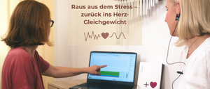 Eine Frau zeigt auf einen Laptop-Bildschirm mit einem Diagramm, während eine andere Frau mit Kopfhörern zusieht. Das Bild hat einen englischen Untertitel über Stress und Herzgleichgewicht.