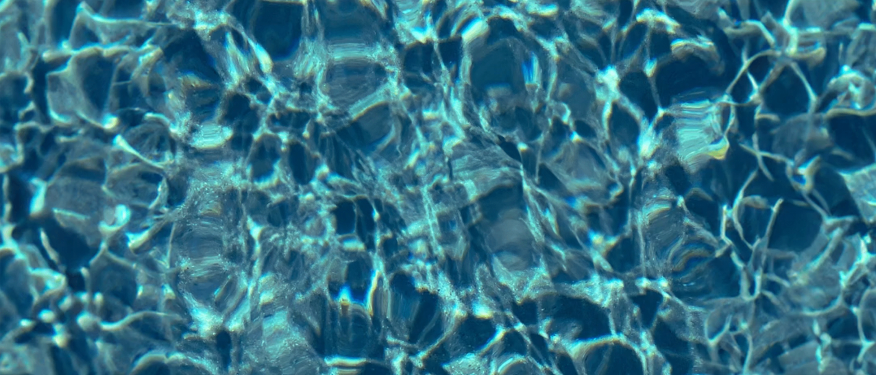 Eine Nahaufnahme von Wasser mit einem blauen Farbton, das Wellen und Reflexionen zeigt.