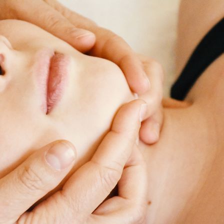 Das Gesicht einer Person wird von einer Hand massiert. Das Gesicht der Person ist leicht verschwommen.