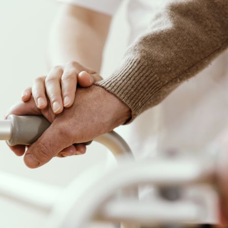 Eine Person mit einer Prothesenhand hält sich an einem Rollatorgriff fest und zeigt eine Nahaufnahme von Hand und Arm.