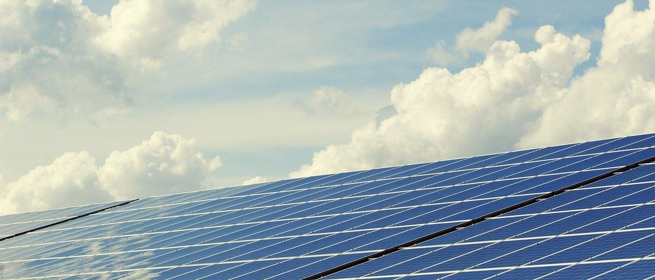 Nahaufnahme eines Solarpanels unter einem strahlend blauen Himmel mit verstreuten Wolken.