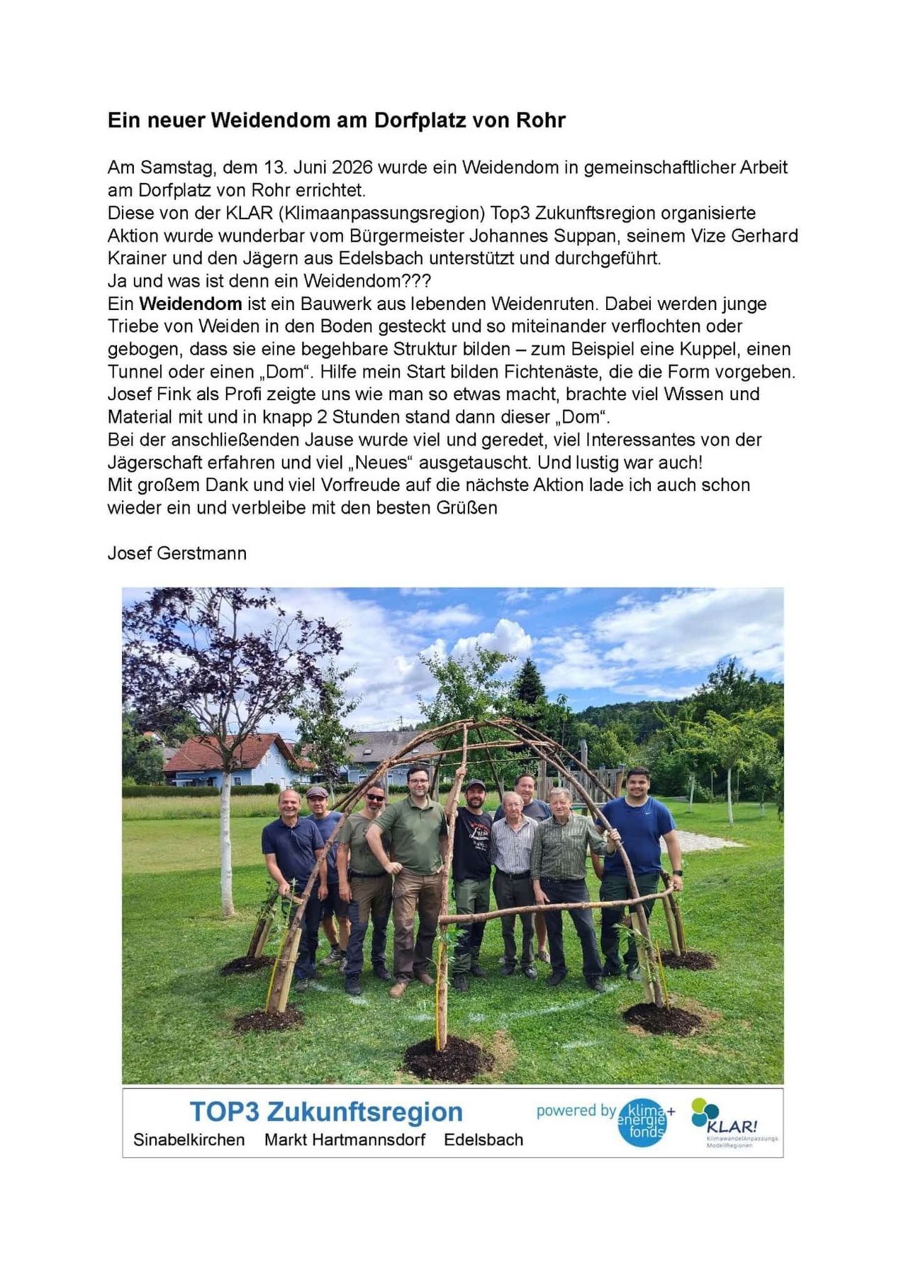 Eine Gruppe von Menschen steht um eine hölzerne Struktur auf einem Feld mit einem Haus im Hintergrund. Josef Gerstmann diskutiert eine Gemeinschaftsaktion mit einem Wehr aus lebenden Bäumen.