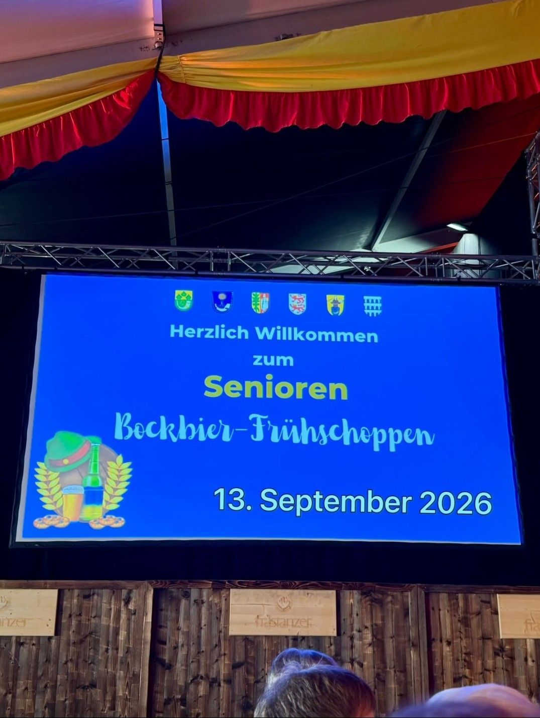Ein blauer Bildschirm zeigt eine Willkommensnachricht für das Senior Bockbier Fruhschopp am 13. September 2026 mit Logos und einem festlichen Design.