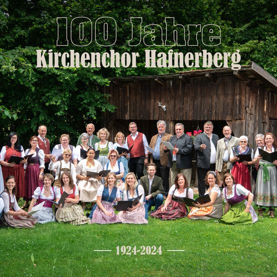 Gruppenfoto des Kirchenchors Hainerberg, 1924-2024, vor einer Holzscheune mit grüner Landschaft im Hintergrund.