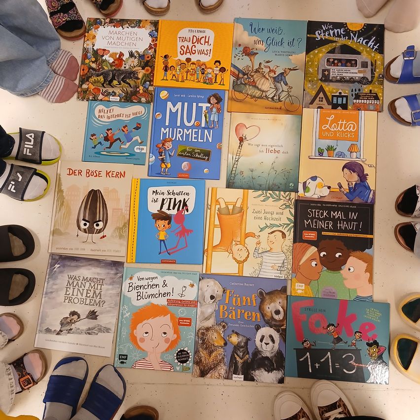 Eine Sammlung von Kinderbüchern ist auf einer weißen Oberfläche ausgelegt. Sie enthält Titel wie 'Mut Murmeln', 'Der Böse Kern' und 'Was Macht Man Mit Einem Problem?' Die Bücher sind bunt und illustriert, geeignet für Kinder.