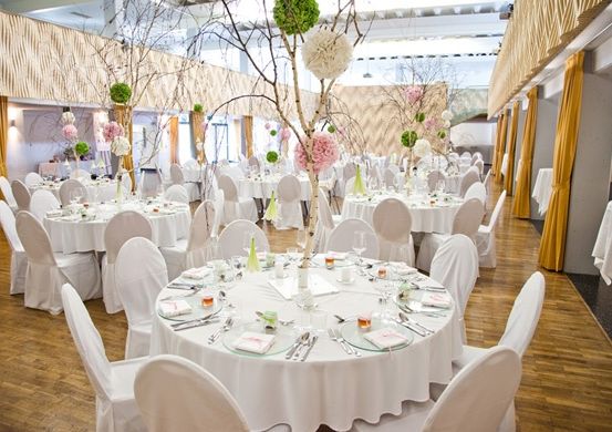 Ein großer Innenbereich für Mahlzeiten mit weißen Tischen und Stühlen, Holzböden und dekorativen Blumen auf den Tischen.