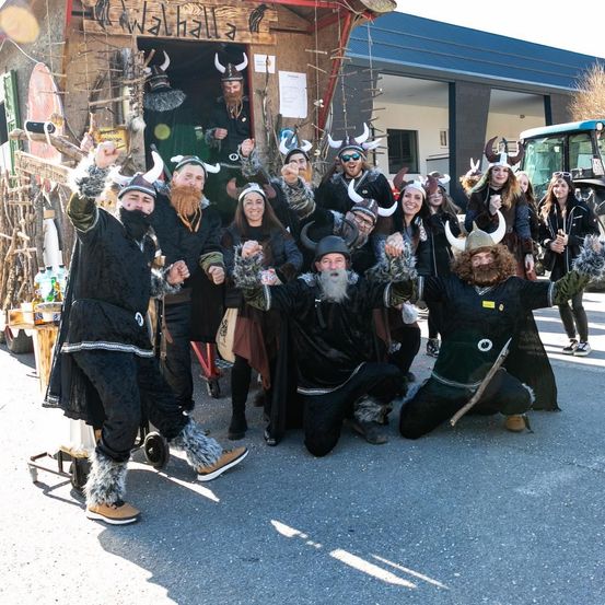 Eine Gruppe von Menschen in Wikingerkostümen posiert für ein Foto vor einem Gebäude mit der Aufschrift 'Walhalla'.