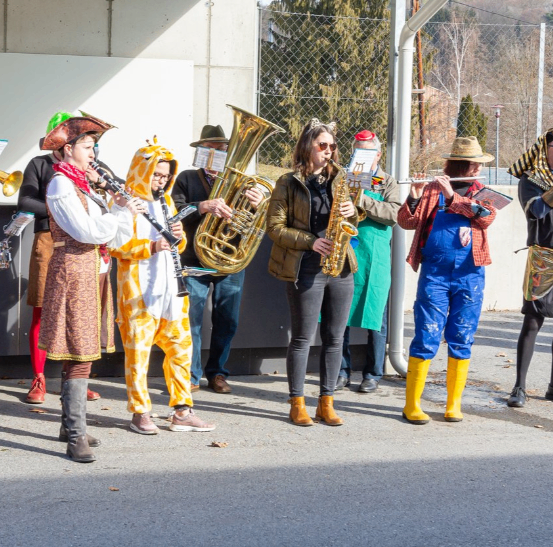 Eine Gruppe von Menschen in verschiedenen Kostümen spielt mit Musikinstrumenten im Freien.