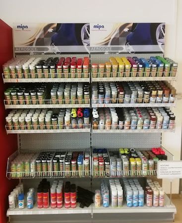 Ein Ladenregal mit Regalen, die mit verschiedenen farbigen Sprühfarben der Marke Mip Aerosole gefüllt sind. Die Regale sind ordentlich organisiert, mit Reihen von Dosen in verschiedenen Farben.