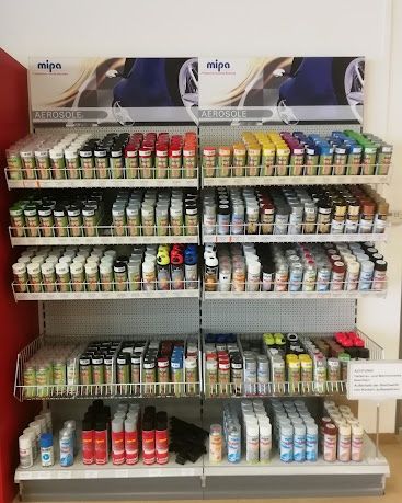 Ein Ladenregal mit Regalen, die mit verschiedenen farbigen Sprühfarben der Marke Mip Aerosole gefüllt sind. Die Regale sind ordentlich organisiert, mit Reihen von Dosen in verschiedenen Farben.