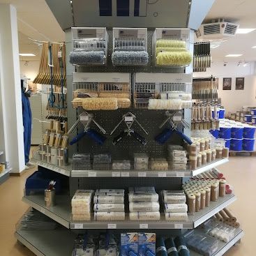 Ein Geschäft mit einer großen Auswahl an Farbwalzen, Pinsel und anderen Malwerkzeugen, die auf Regalen mit Plastikbehältern und Aufbewahrungsboxen angeordnet sind.