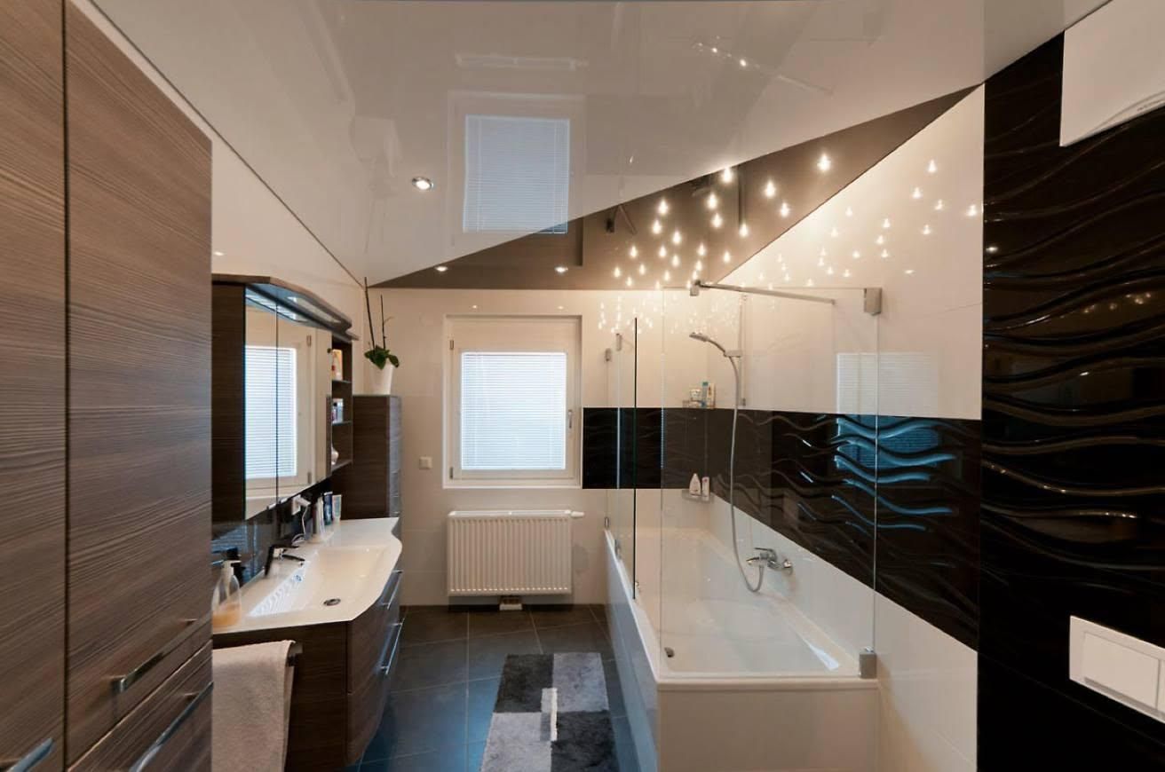 Ein modernes Badezimmer mit einer weißen Badewanne, einer Glasdusche und schwarz-weißen gefliesten Wänden. Ein Waschbecken mit einem Wasserhahn und einem Spiegel befindet sich links, und ein Heizkörper ist an der Wand angebracht.