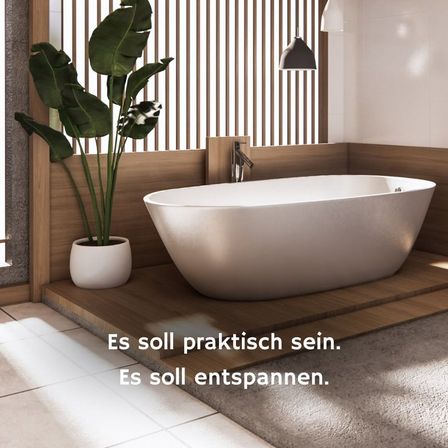 Eine moderne Badewanne in einem Badezimmer mit einer Holzwand und einem Topf mit einer Pflanze. Die Badewanne ist weiß und hat einen Wasserhahn. Das Badezimmer hat einen Holzboden und einen weißen Fliesenboden. Die Worte 'Es soll praktisch sein. Es soll entspannen' sind an der Wand geschrieben.
