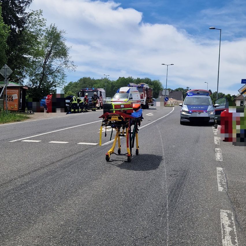 An accident scene with emergency vehicles parked on the road. Firefighters are attending to a car, and a police car is nearby.