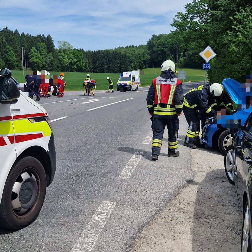 Emergency personnel attend to an accident on the road. One person is on a stretcher and another is examining a damaged vehicle.