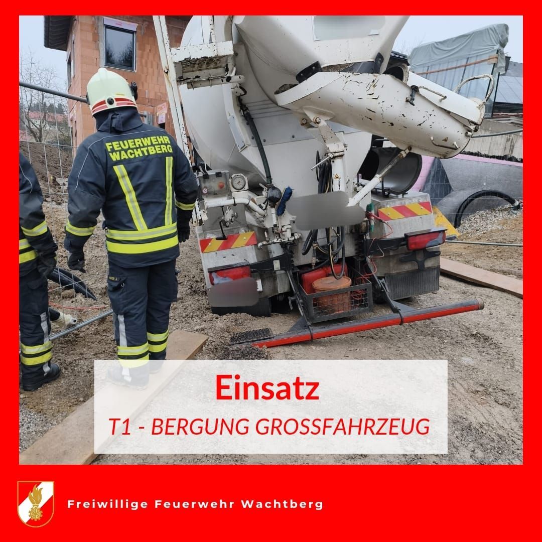 Zwei Feuerwehrleute in Uniformen stehen neben einem großen Lastwagen mit einem Mischer auf dem Rücken. Die Worte 'Einsatz T1' und 'BERGUNG GROSSFAHRZEUG' sind auf dem LKW geschrieben.