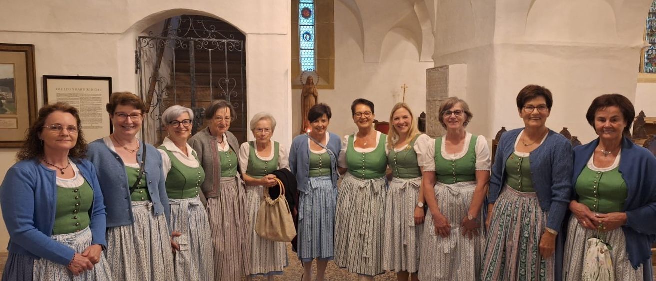 Eine Gruppe von Frauen in traditioneller bayerischer Kleidung steht in einer Kirche. Sie lächeln für die Kamera.