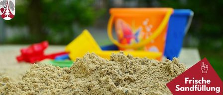 A sandy area with toys in the background. A bucket with a fish design. The word Friday Sand is on the right.