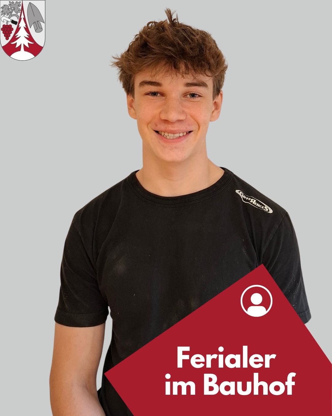 Ein lächelnder junger Mann mit braunen Haaren trägt ein schwarzes T-Shirt mit einem weißen Logo auf der linken Brust. Ein roter Dreieck am unteren rechten Rand mit dem Text 'Ferialer'.