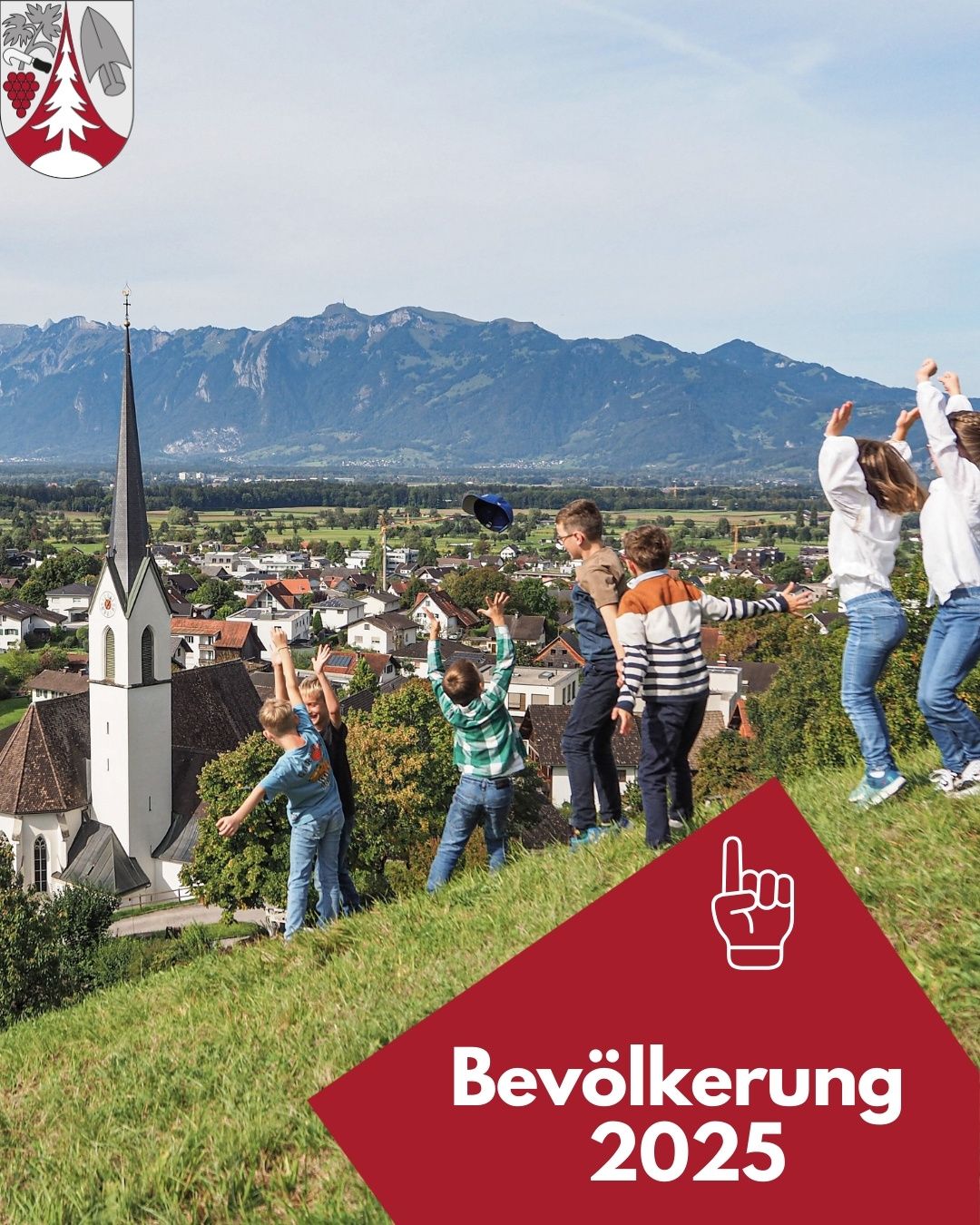 Kinder spielen fröhlich auf einem Hügel und blicken auf ein Dorf mit einem Kirchturm und Bergen im Hintergrund.
