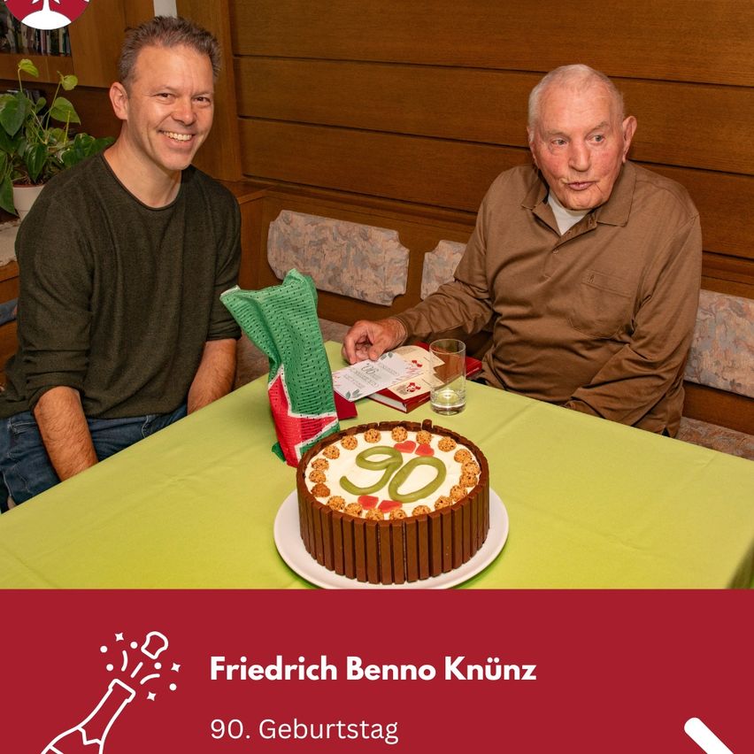 Zwei Männer sitzen an einem Tisch mit einem Kuchen, auf dem 90 steht, und feiern einen Geburtstag.