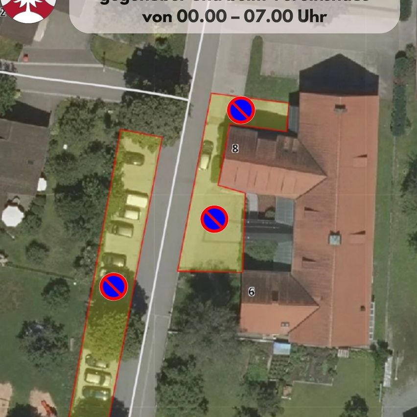 Luftaufnahme eines Parkplatzes mit markierten Parkverbotszonen, den Nummern 6 und 8, und einem Gebäude mit schwarzem Dach.