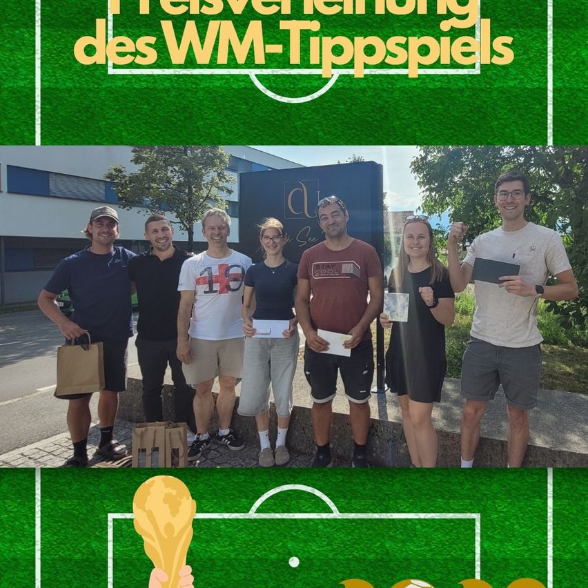 Eine Gruppe von Menschen steht draußen und hält Papiere in der Hand und lächelt. Sie stehen vor einem Gebäude mit einem Schild, auf dem 'Al' steht. Der Hintergrund ist ein grünes Fußballfeld mit einem Pokal im Vordergrund.